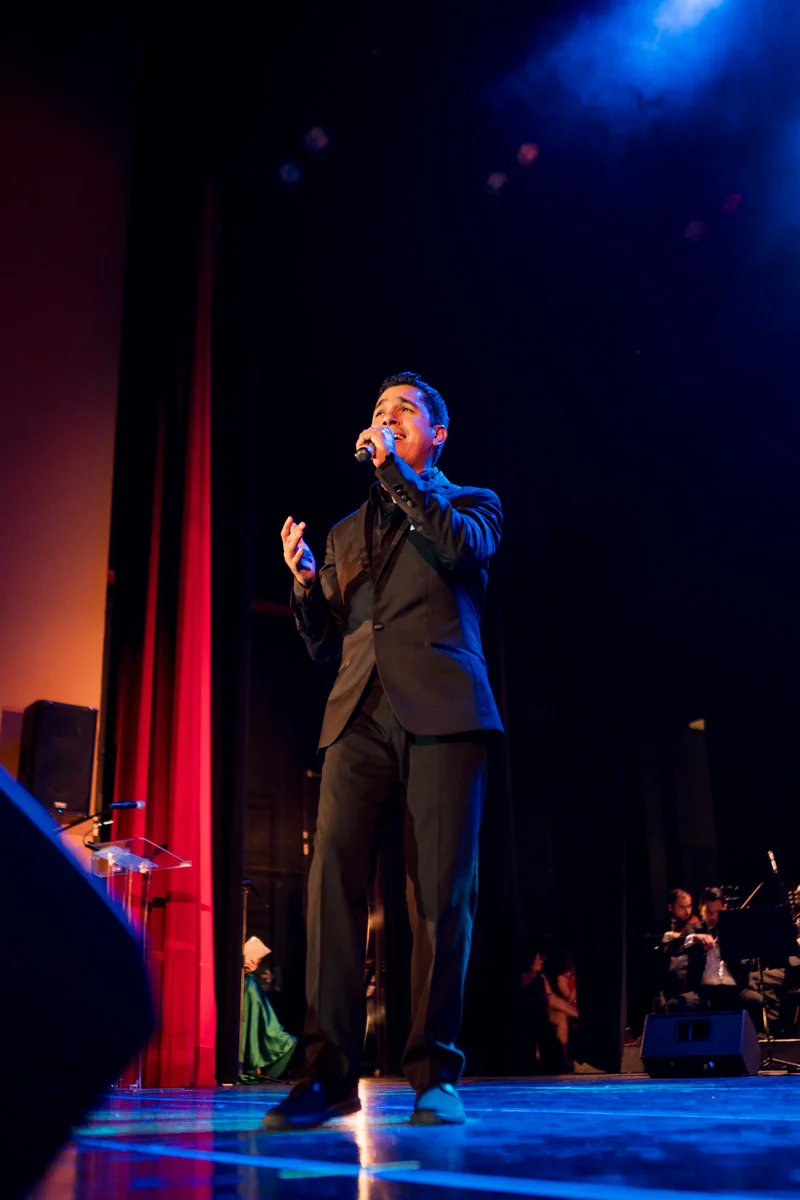 Louis Lara interpretando una canción en un escenario iluminado en azul