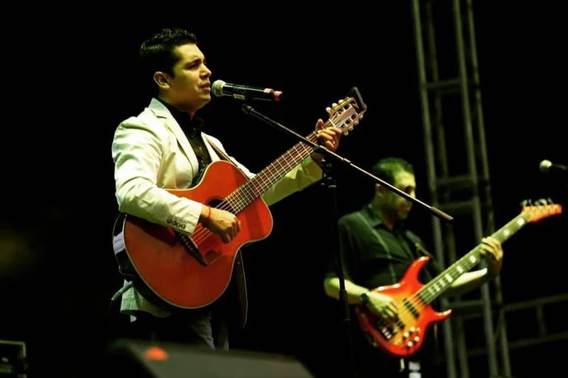 Louis Lara cantando y tocando la guitarra acompañado de músicos